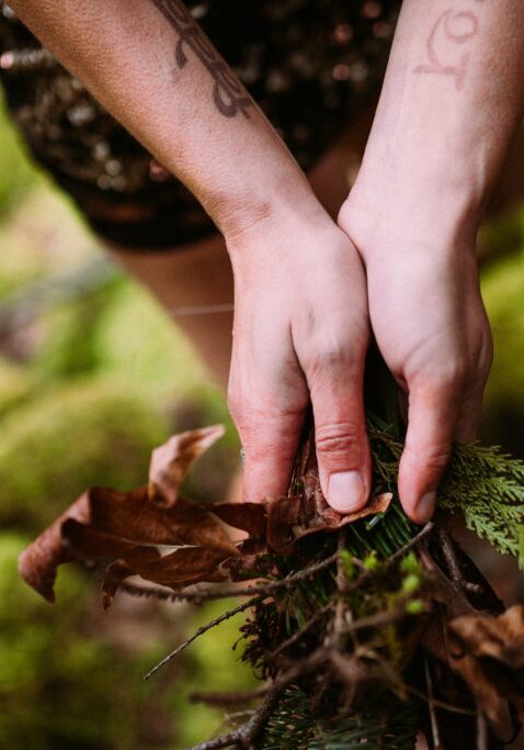 A woman's hands offering intuitive energy healing sessions in the forest, surrounded by moss.