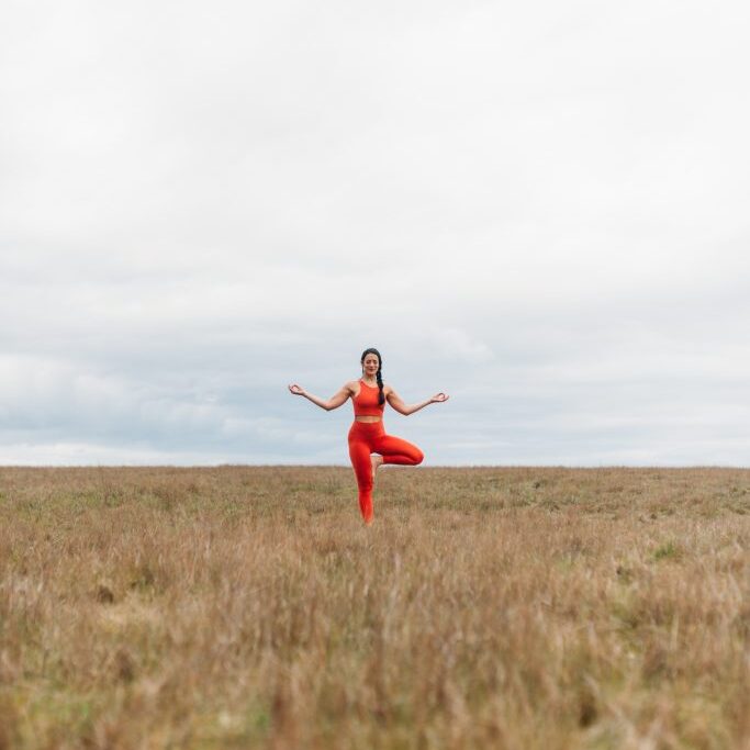 Minda Lane, dressed in an orange outfit, is standing in a field.